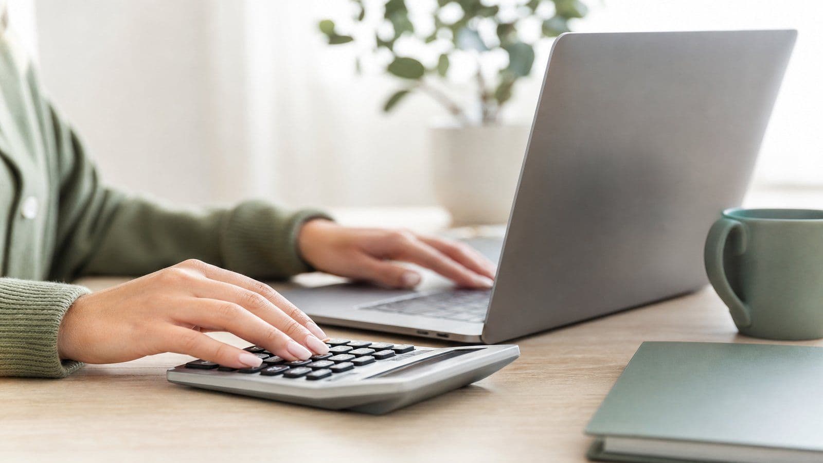 A small-business owner works through her monthly bookkeeping tasks at a calculator