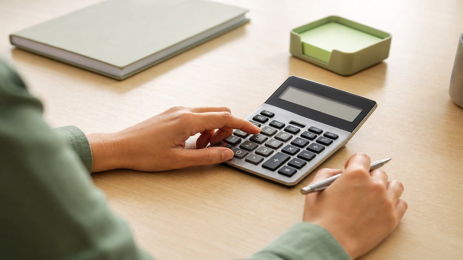 Careful hands checking figures on a calculator, the kind of detail work good disclosures rely on